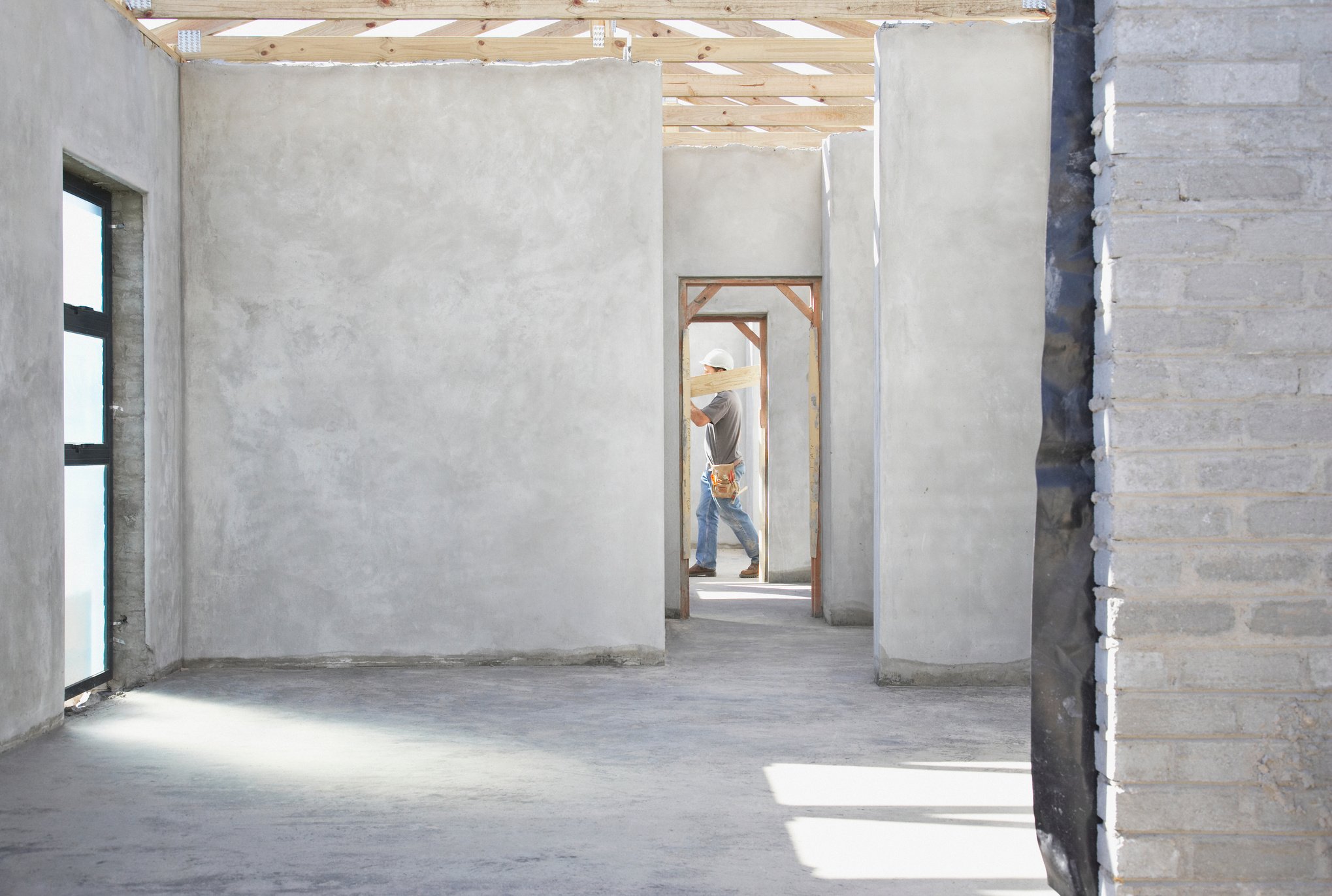 Construction worker carrying lumber on construction site